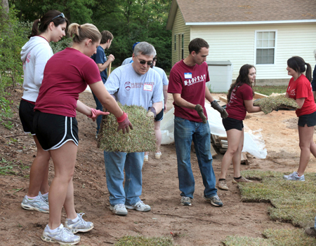 President Barron helping to lay sod along with FSU students volunteering at a recent Habitat for Humanity build.