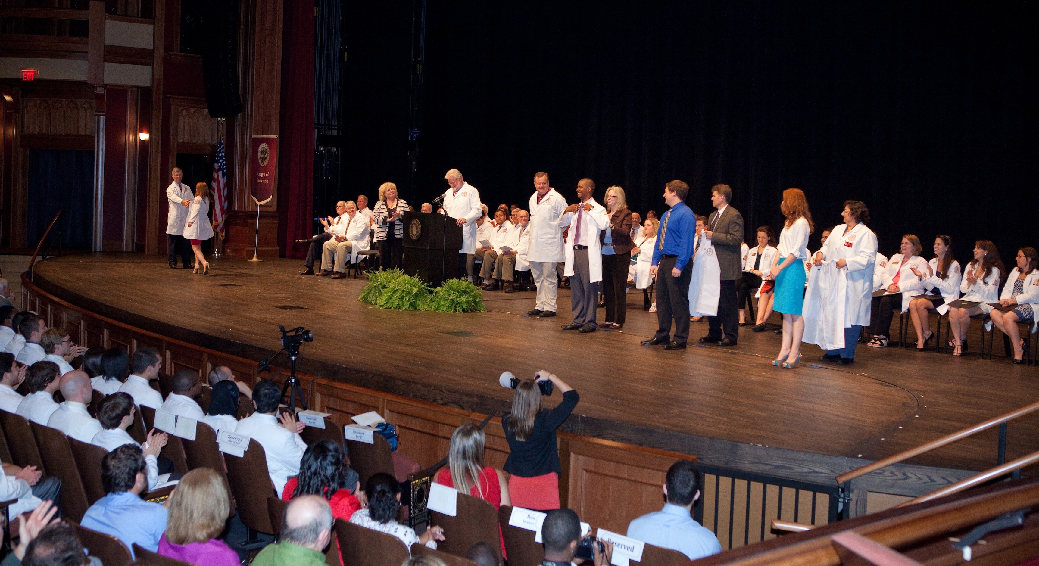 Family members watch proudly from the audience as the students are called one by one to receive their white coats.