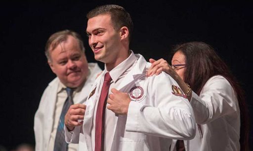 Nicholas Casler is coated by his mother, Dr. Alix Casler, at the College of Medicine's White Coat Ceremony Friday, Aug. 12.