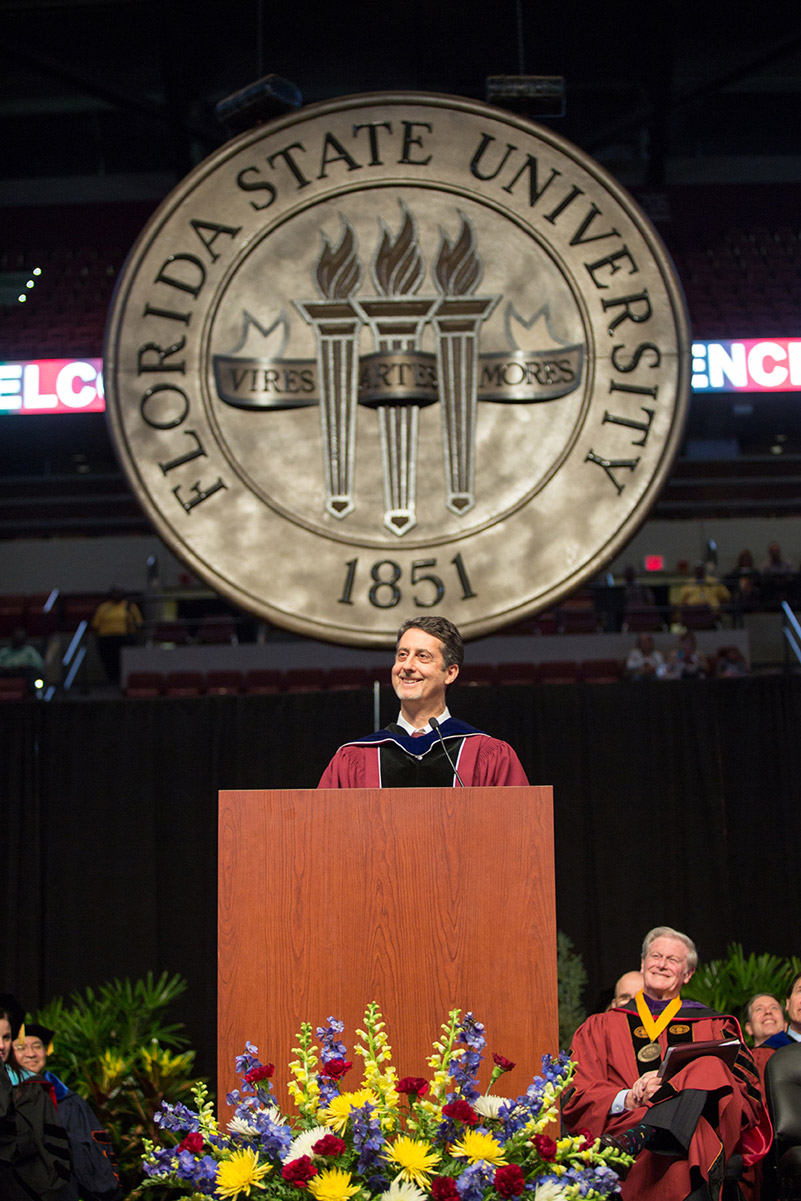 FSU Professor Joseph Schlenoff addresses graduates in front of a new decorative seal created by the FSU Master Craftsmen Studio. It will be displayed at all future commencement ceremonies.