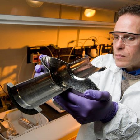 Lance Cooley, an ASC scientist and professor at the FAMU-FSU College of Engineering, examines the cross-section of an RF cavity, a critical component of a particle accelerator. (Reidar Hahn/Fermilab)