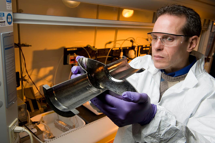 Lance Cooley, an ASC scientist and professor at the FAMU-FSU College of Engineering, examines the cross-section of an RF cavity, a critical component of a particle accelerator. (Reidar Hahn/Fermilab)