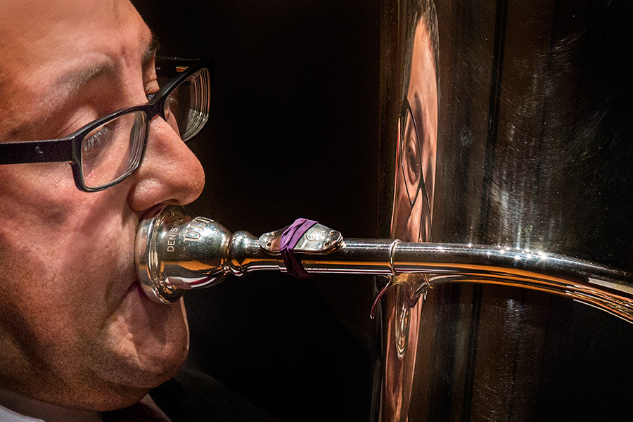 Justin Benavidez, assistant professor of Tuba and Euphonium, is reflected in his instrument during his faculty recital.