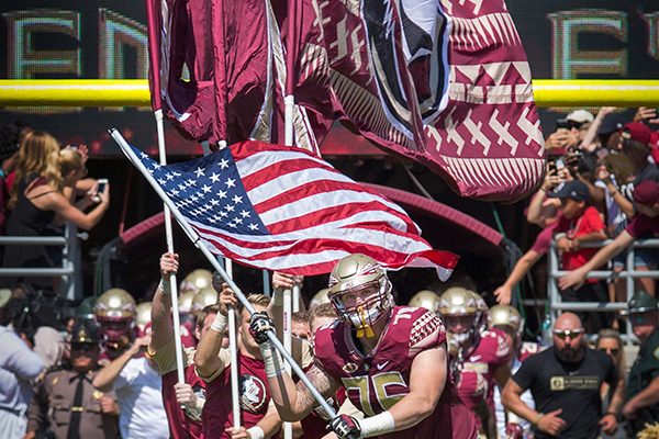The Florida State University Seminoles take the field with the American flag during pregame of the Veterans Appreciation game.
