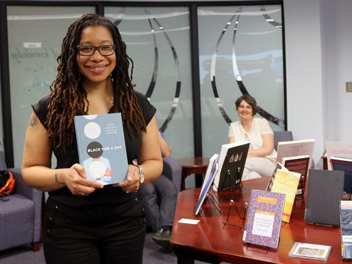 Associate Professor of English Alisha Gaines with her book “Black for a Day: White Fantasies of Race and Empathy.” (Photo: University Communications)