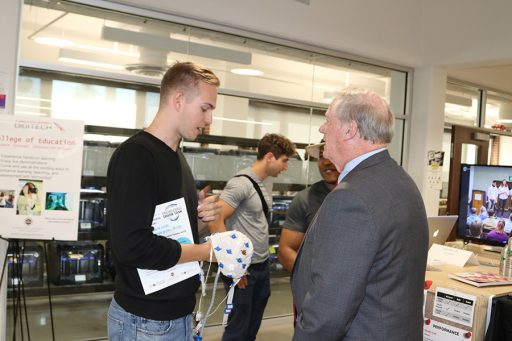 Junior Alex Koberda explains his idea to use an EEG cap to test witness validity to President John Thrasher. (Photo: Univesity Communications)