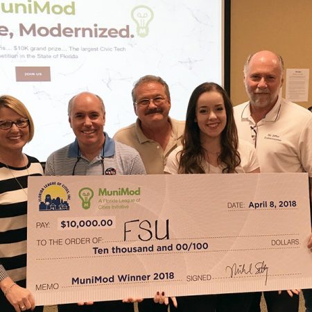 MuniMod judges present $10,000 check to FSU student Molly Cloonan. (from left) Gwen Johns, Mount Dora City Clerk & President of the Florida Association of City Clerks; Mike Lester, NASA Technology Transfer Program Director; Mayor Gary Bruhn, Town of Windermere & President of the Florida League of Mayors; Molly Cloonan, Florida State University student; Commissioner Gil Ziffer, City of Tallahassee & President of the Florida League of Cities; Toni Bleiweiss, CGCIO, Lee County Clerk of Courts & President of the Florida Local Government Information Systems Association; and Jim Hanson, Retired Town Administrator, Orange Park, & President of the Florida City & County Management Association.