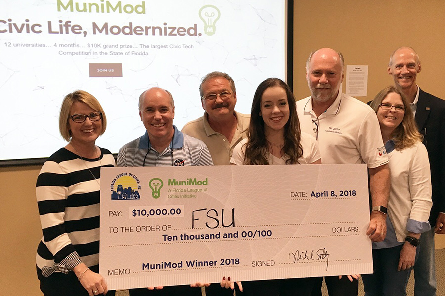 MuniMod judges present $10,000 check to FSU student Molly Cloonan. (from left) Gwen Johns, Mount Dora City Clerk & President of the Florida Association of City Clerks; Mike Lester, NASA Technology Transfer Program Director; Mayor Gary Bruhn, Town of Windermere & President of the Florida League of Mayors; Molly Cloonan, Florida State University student; Commissioner Gil Ziffer, City of Tallahassee & President of the Florida League of Cities; Toni Bleiweiss, CGCIO, Lee County Clerk of Courts & President of the Florida Local Government Information Systems Association; and Jim Hanson, Retired Town Administrator, Orange Park, & President of the Florida City & County Management Association.