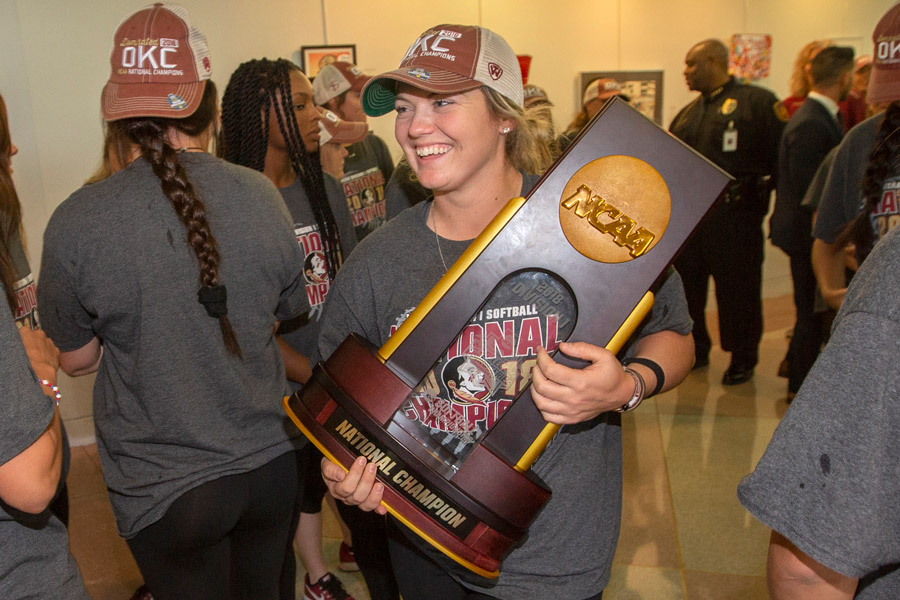 FSU senior Jessie Warren carries the 2018 NCAA Softball National Championship trophy into Tallahassee City Hall, where the team was honored by city commissioners on June 6, 2018. (FSU Photography Services)