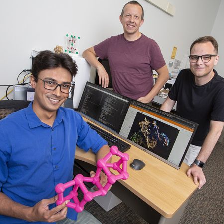 Doctoral student Kevin Ryan (seated) developed a machine learning model to predict new chemical compounds. Standing are Professor Michael Shatruk (left) and graduate student Jeff Lengyel (right).