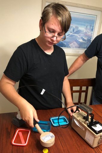 Rising 8th-grader Joe Hovis performs a measurement in his home with the equipment provided by camp instructors.