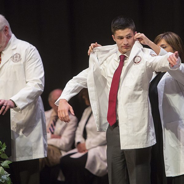 Jimmy Brown receives a white physician's coat during a 2017 ceremony at the FSU College of Medicine. Brown, a member of the M.D. Class of 2021, became the first student to recieve the Nancy Van Vessem, M.D. Memorial Scholarship. (FSU Photography Services)