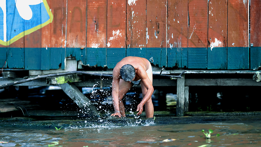 Marcos Colón, “Cooling Down in the Sun,” a man takes a bath outside his home in Belén, Iquitos, Peru, March 2020.