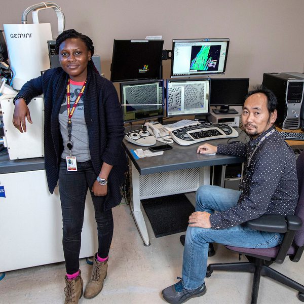 Abiola Temidayo Oloye, left, a fifth-year doctoral candidate and the lead author of a study published in Superconductor Science and Technology, at an electron microscope with Fumitake Kametani, an associate professor of mechanical engineering and principal investigator for the study at the FAMU-FSU College of Engineering. (Mark Wallheiser/FAMU-FSU College of Engineering)