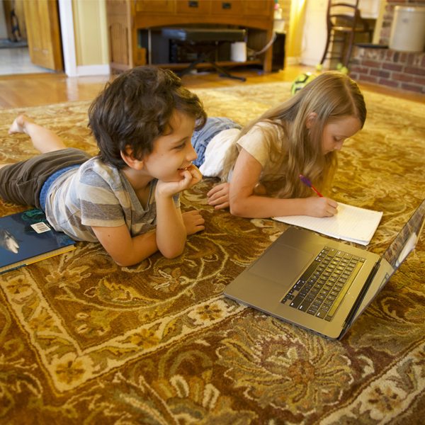 A first-grade student and fourth-grade student learning from home through the digital academy at Gilchrist Elementary School. (Courtesy of Robert Schoen)