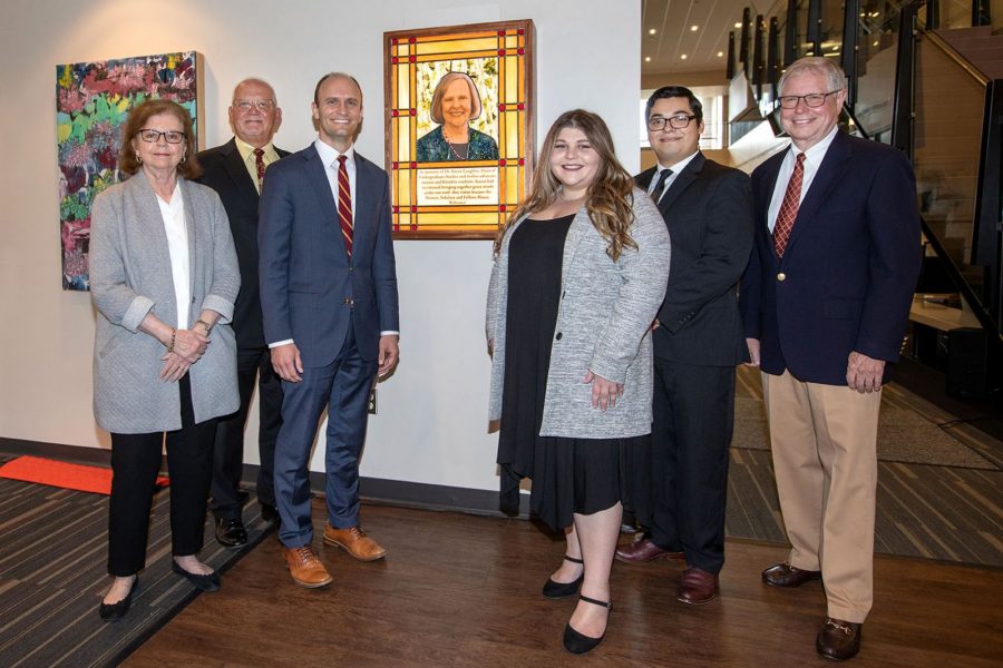 From left: Anne Rowe, Bruce Janasiewicz, Joe O'Shea, Cara Axelrod, Brendan Gonzalez and Jim Lee gather around the stained-glass window was unveiled in honor of the late Karen Laughlin during a celebration of her legacy Oct. 21, 2021, at Florida State University’s Honors, Scholars and Fellows house. (FSU Photography Services)