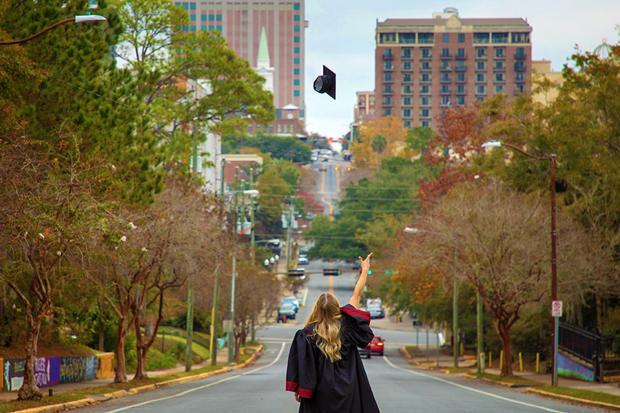 An FSU graduate tosses her cap in the air while looking up College Avenue Dec. 9, 2021. (FSU Photography Services)