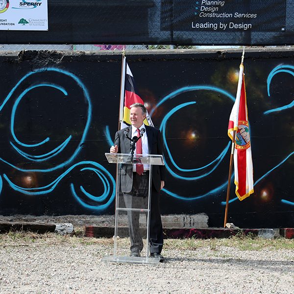 President Richard McCullough helps celebrate the unveiling of a mural created by members of the Seminole Tribe of Florida.