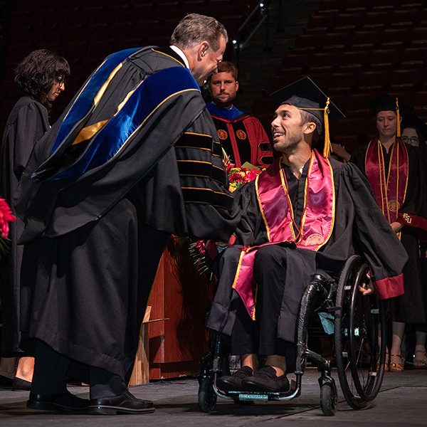 Will Cotter shakes hands with Sam Huckaba, dean of the College of Arts and Sciences, during the summer 2022 commencement ceremony at 7 p.m. July 29. (FSU Photography Services)