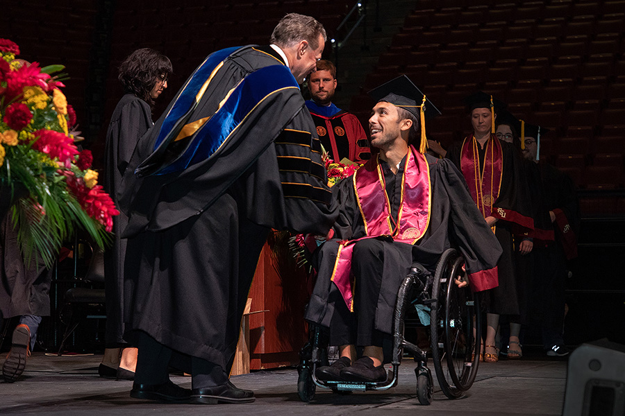 Will Cotter shakes hands with Sam Huckaba, dean of the College of Arts and Sciences, during the summer 2022 commencement ceremony at 7 p.m. July 29. (FSU Photography Services)