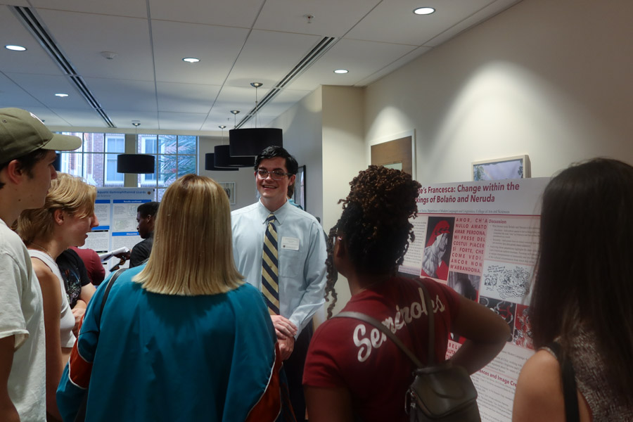 Student Harrison Betz speaking with other students at the 2022 President's Showcase of Undergraduate Research Excellence.