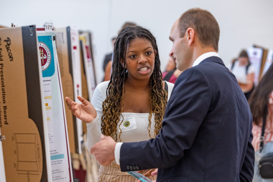 Associate Provost and Dean of the Division of Undergraduate Studies Joe O'Shea visits with a student researcher presenting at the 23rd annual Undergraduate Research Symposium in the Student Union ballrooms, April 6 2023. (FSU Photography Services)