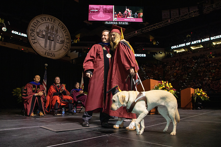 Florida State University's President Richard McCullough poses with a graduate and their service animal during spring commencement Friday, May 5, 2023, at the Donald L. Tucker Civic Center. (FSU Photography Services)
