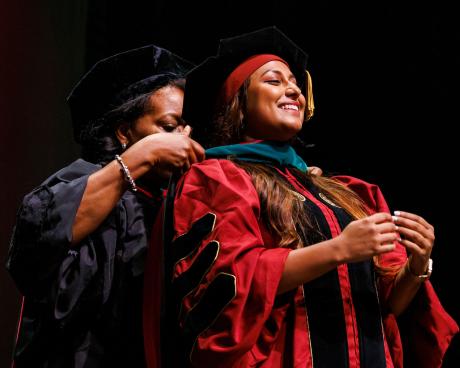 Fort Pierce Regional Campus Dean Juliette Lomax-Homier hoods Dr. Aariha Ali, whom she delivered 25 years earlier. (Photo by Colin Hackley for the FSU College of Communication.)