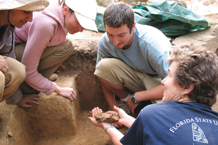 Nancy T. de Grummond, director of excavations and archeological research at Cetamura del Chianti, examines an artifact with students. (FSU International Programs)