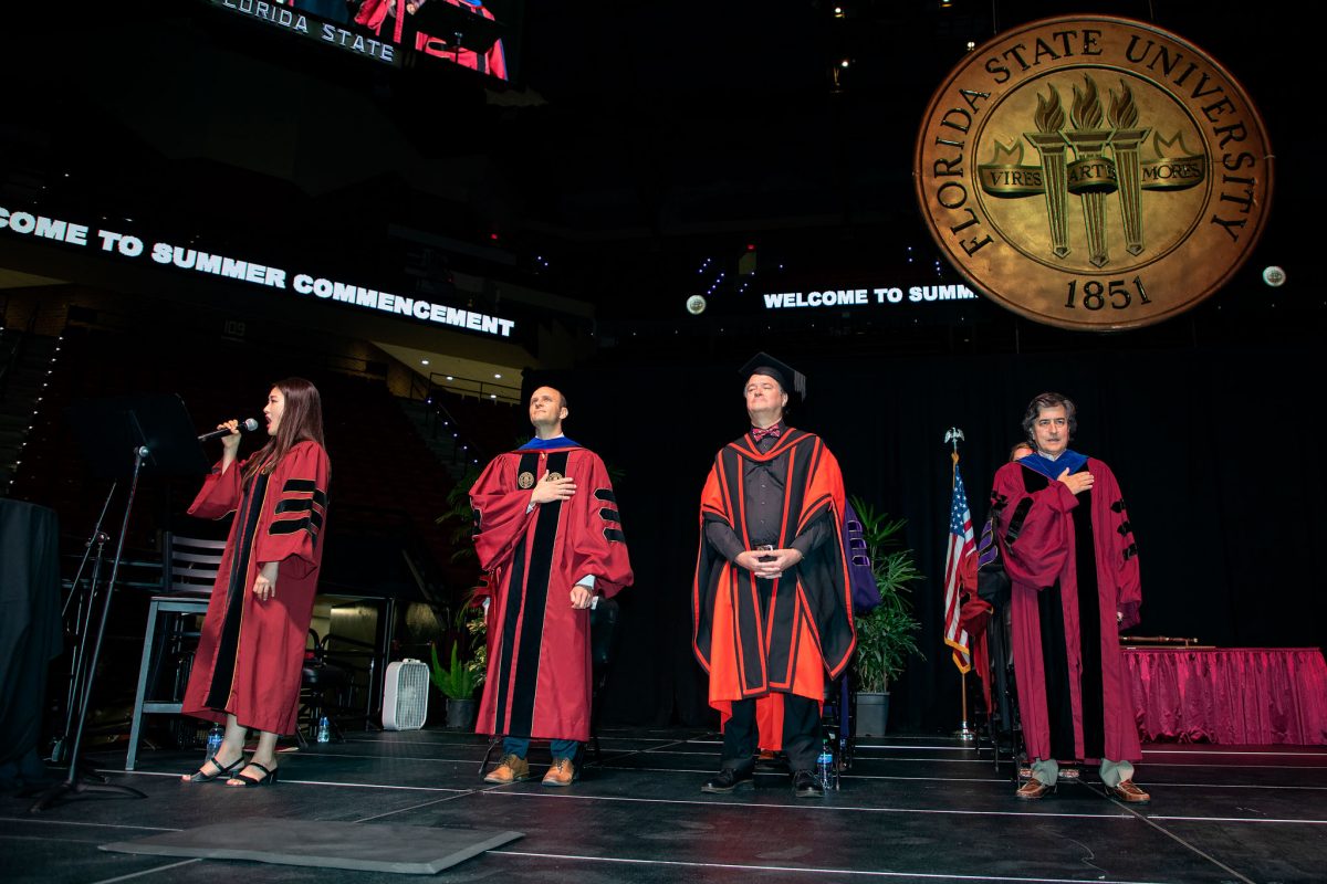 Doctoral student Ye Ji Lee sings the National Anthem with Joe O’Shea, associate provost and dean of Undergraduate Studies, Mark Riley, dean of the graduate school and Provost Jim Clark at FSU's summer doctoral hooding ceremony Friday, Aug. 4, 2023. (FSU Photography)
