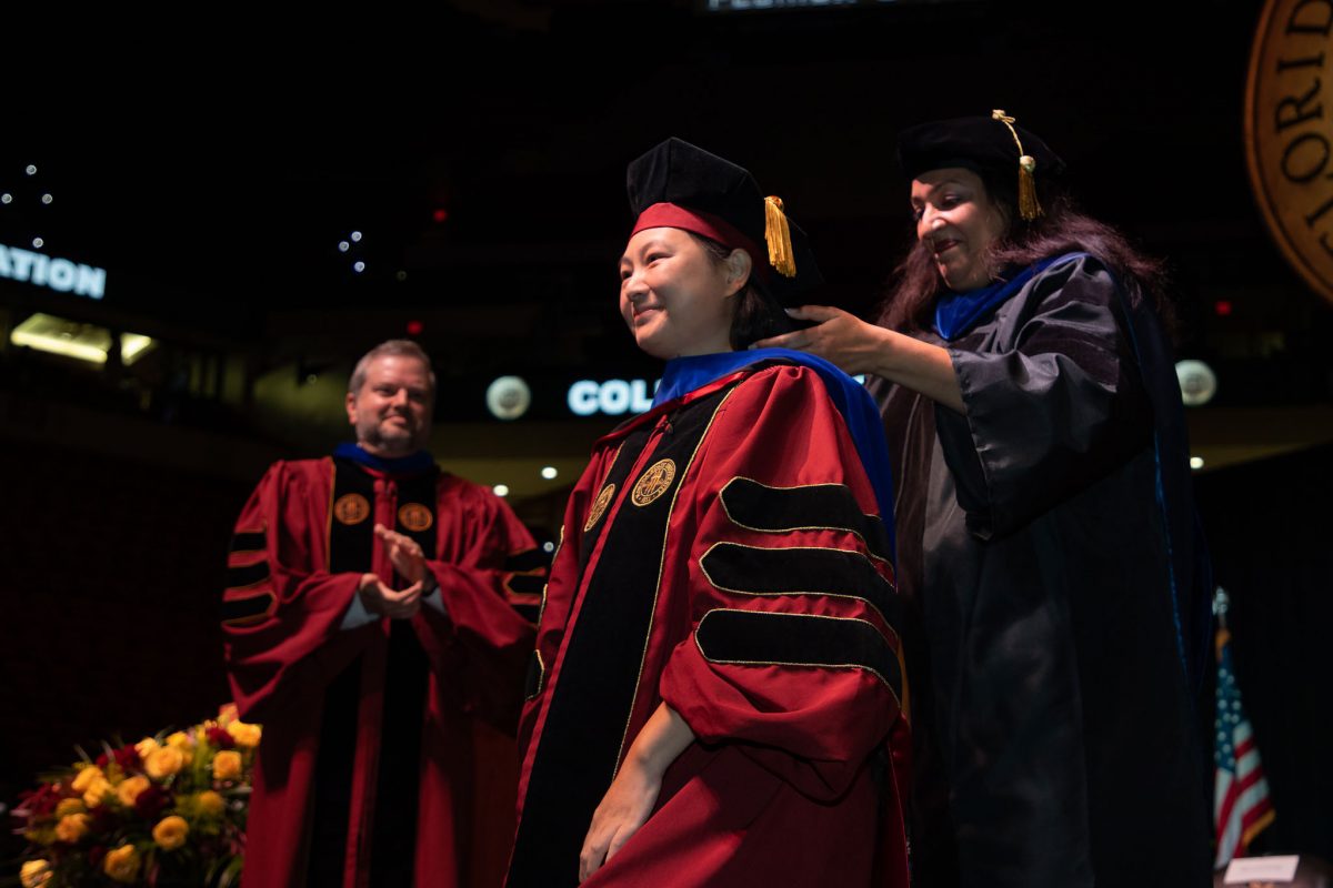 A Florida State University faculty hoods a doctoral graduate the summer doctoral hooding ceremony Friday, Aug. 4, 2023, at the Donald L. Tucker Civic Center. (FSU Photography)