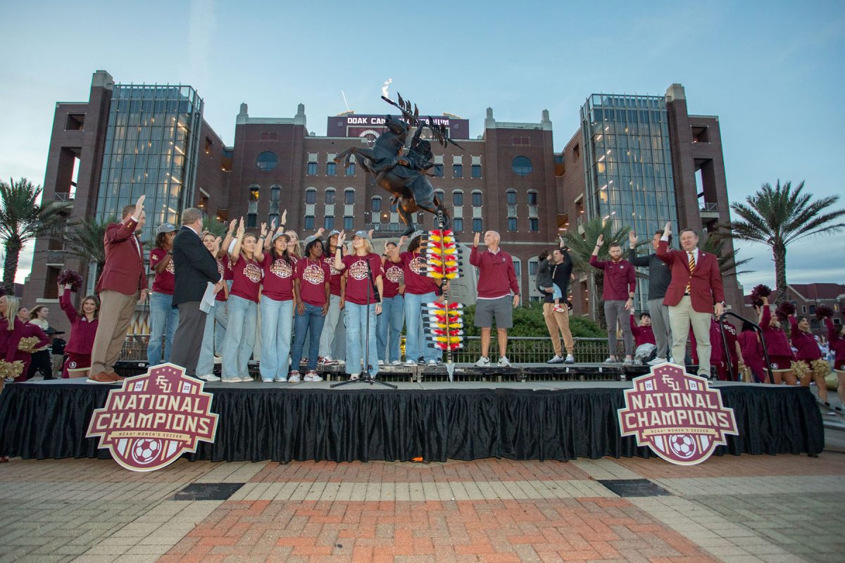 President Richard McCullough and Florida State Women's Soccer team players and coaches do the Tomahawk Chop in front of the Uconquered Statue, Dec. 5, 2023. (FSU Photography)
