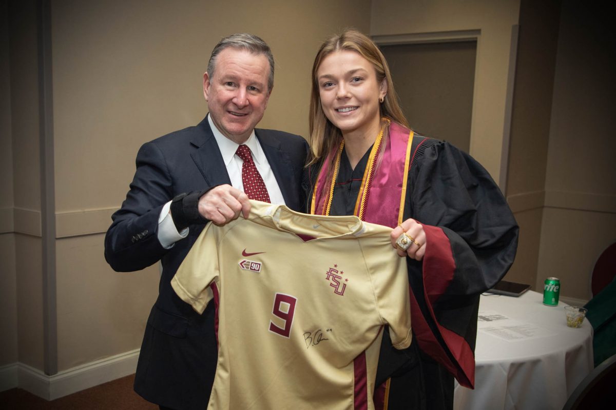 Florida State University President Richard McCullough and Florida State women's soccer player Beata Olsson celebrate during the fall commencement ceremony Friday, Dec. 15, 2023, at the Donald L. Tucker Civic Center. (FSU Photography Services)