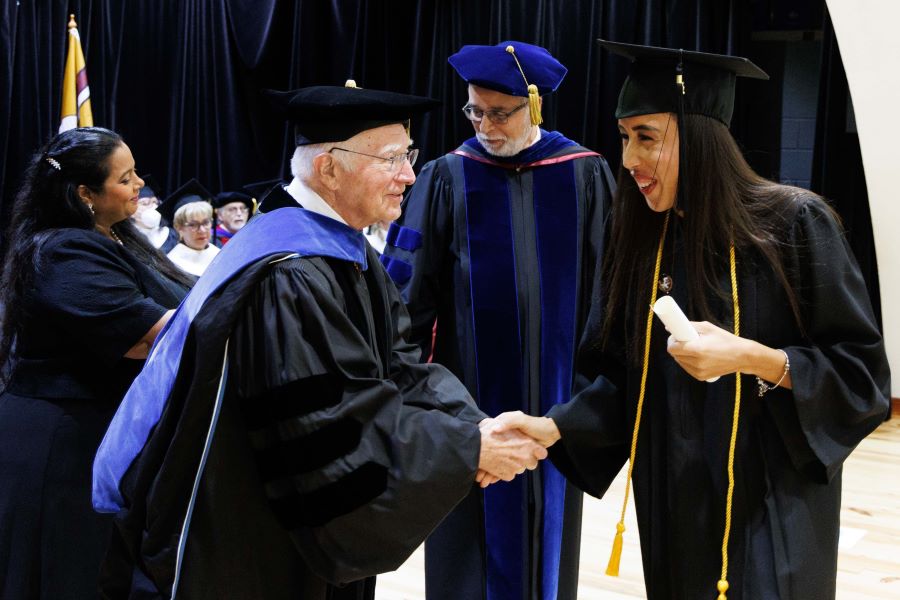 Director of FSU International Programs shakes hands with FSU-Panama graduate Shaina Rosario during FSU-Panama's 2023 commencement ceremony Tuesday, Dec. 5, at the City of Knowledge Convention Center in Panama City, Panama. (FSU-Panama, Pedro Ahues)