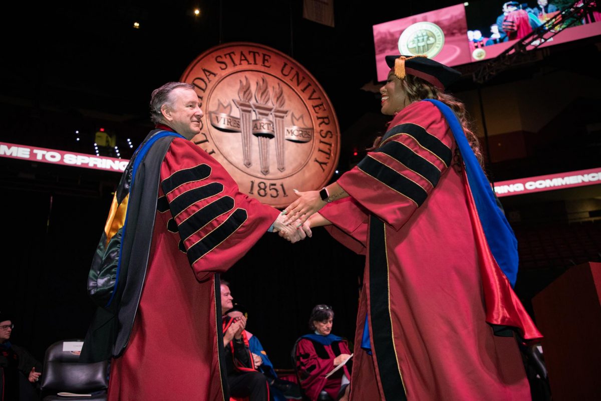 FSU President Richard McCullough shakes a graduate's hand during FSU's spring doctoral hooding ceremony Friday, May 3, 2024, at the Donald L. Tucker Civic Center. (FSU Photography)
