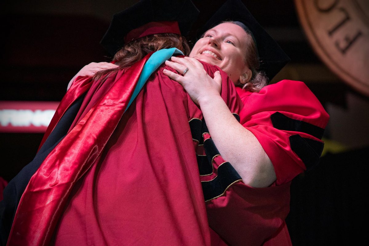 A Florida State University faculty member embraces a graduate during the spring doctoral hooding ceremony Friday, May 3, 2024, at the Donald L. Tucker Civic Center. (FSU Photography)