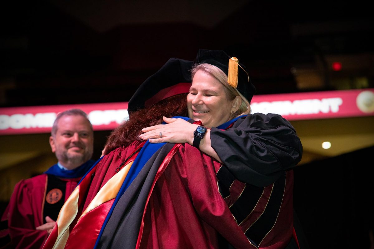 A Florida State University faculty member embraces a graduate during the spring doctoral hooding ceremony Friday, May 3, 2024, at the Donald L. Tucker Civic Center. (FSU Photography)