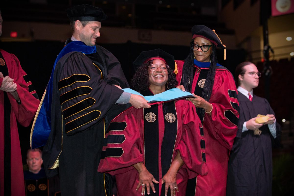 Two Florida State University faculty members hood a doctoral graduate at the spring doctoral hooding ceremony Friday, May 3, 2024, at the Donald L. Tucker Civic Center. (FSU Photography)