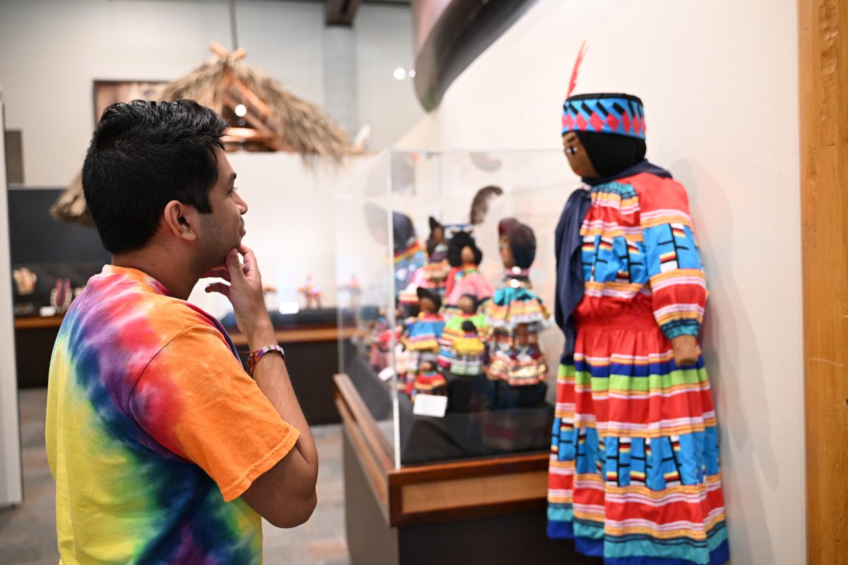 An FSU student volunteer examines an exhibit at the Ah-Tah-Thi-Ki Museum during the Seminole Tribe of Florida's annual American Indigenous Arts Celebration in early November 2024. (Aiden Briesacher)