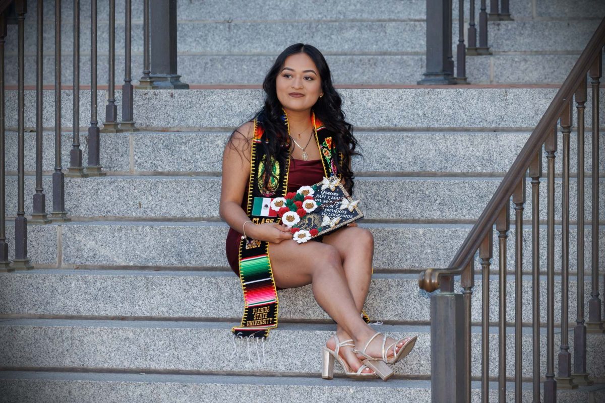 A graduate poses on the steps of the Westcott Building Dec. 12, 2024 in Westcott Plaza. (FSU Photography)