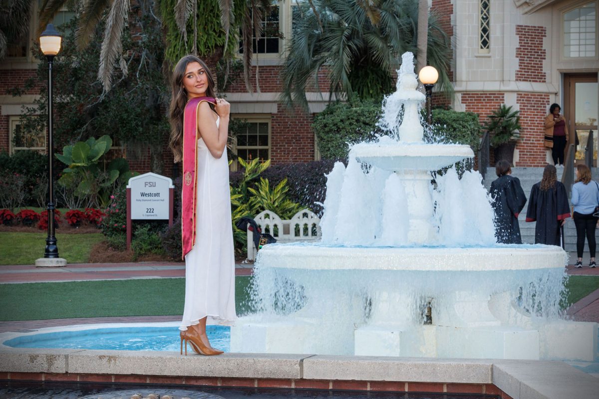 A graduate poses in front of Westcott Fountain Dec. 12, 2024 in Westcott Plaza. (FSU Photography)