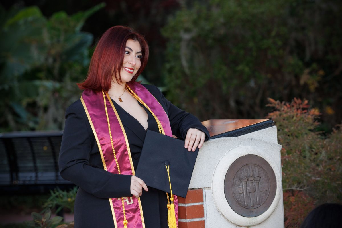 A graduate takes photos by Westcott Fountain Dec. 12, 2024 in Westcott Plaza. (FSU Photography)