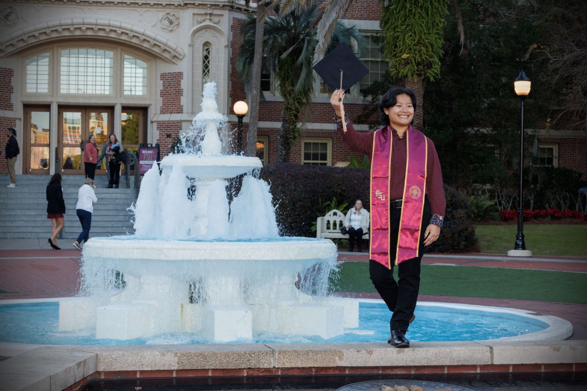 A graduate poses in front of Westcott Fountain Dec. 12, 2024 in Westcott Plaza. (FSU Photography)