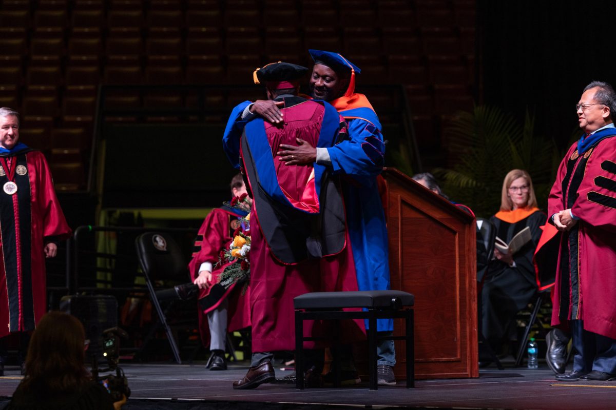 A Florida State University faculty member embraces a graduate during the fall doctoral hooding ceremony Friday, Dec. 13, 2024, at the Donald L. Tucker Civic Center. (FSU Photography)