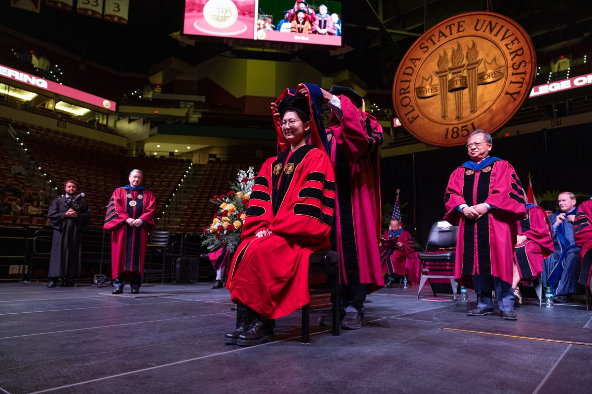 A Florida State University faculty member hoods a graduate during the fall doctoral hooding ceremony Friday, Dec. 13, 2024, at the Donald L. Tucker Civic Center. (FSU Photography)