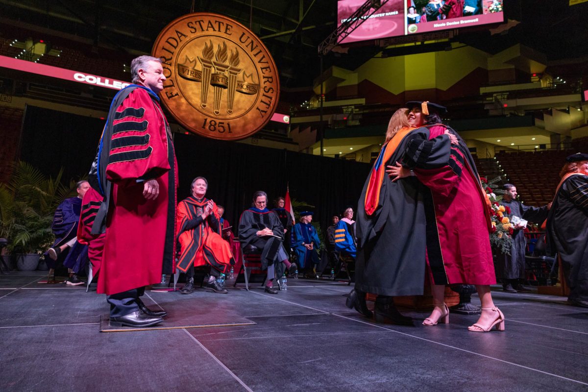 A Florida State University faculty member embraces a graduate during the fall doctoral hooding ceremony Friday, Dec. 13, 2024, at the Donald L. Tucker Civic Center. (FSU Photography)