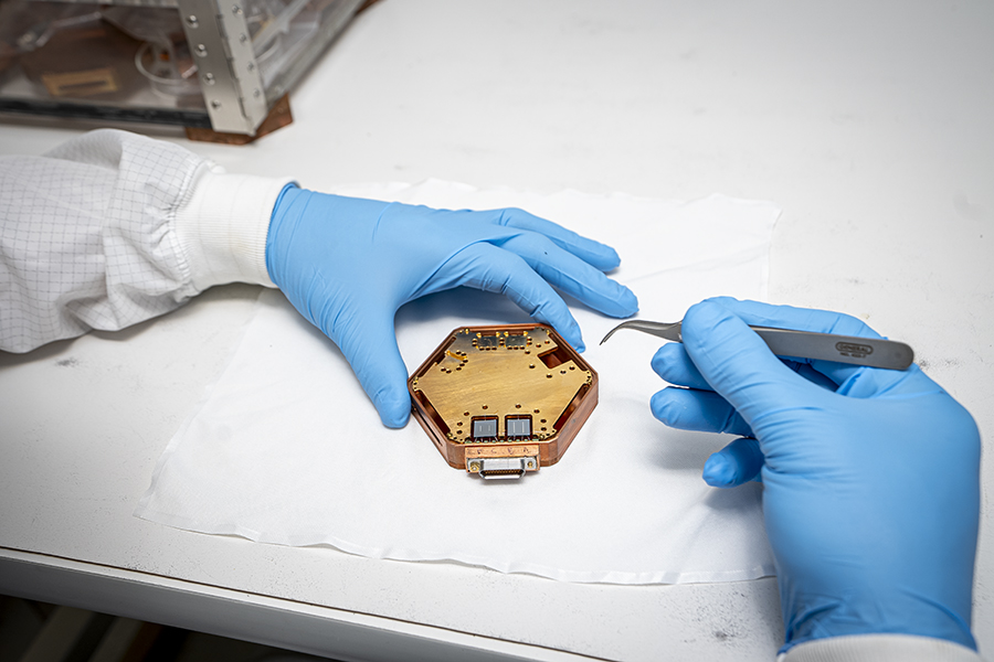 Sensitive detectors let TESSERACT search for dark matter in mass ranges no other experiment has explored. Roger K. Romani, University of Berkeley graduate student, works on the project in a cleanroom. (Marilyn Sargent/Berkeley Lab)