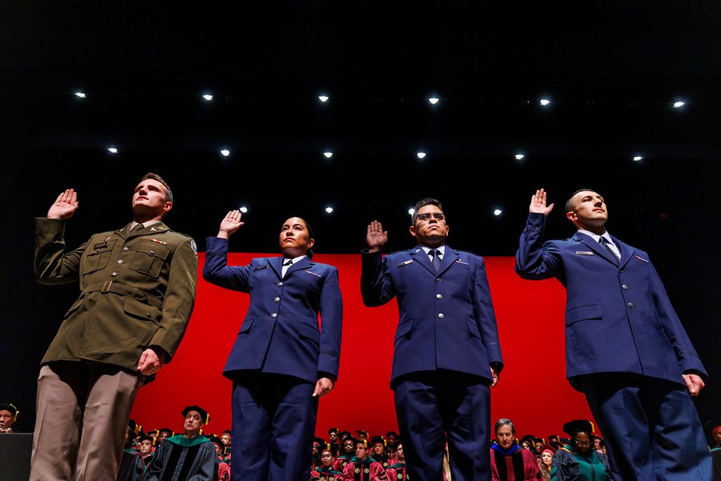 Military members of the M.D. Class of 2025, from left to right, Ryan Peacock, Erika Balazs, Mike Llerena and Nathan Steineck, renew their oath or service during Saturday’s commencement ceremony.