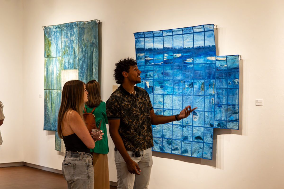 Visitors examine work by Chole Sailor at the opening of “Origins & Afterlives.” (Jamie Rager/FSU College of Fine Arts)