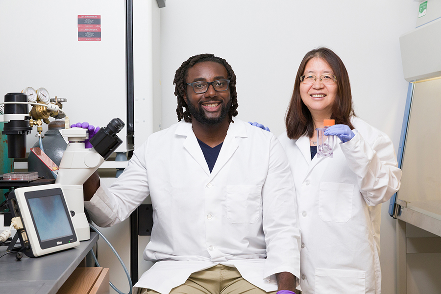 From left, graduate student Justice Ene and Professor Yan Li from the Department of Chemical and Biomedical Engineering pose in a lab in Florida State University’s Interdisciplinary Research and Commercialization Building. Li and her team developed a new way to mass-produce extracellular vesicles, a promising tool for health care because of their ability to contain medicines and to deliver them to hard-to-reach parts of the body. Li is holding an example of a vertical-wheel bioreactor used in this research. (Scott Holstein/FAMU-FSU College of Engineering)